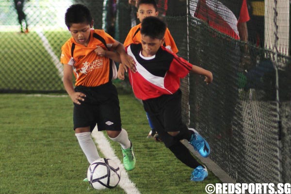 One of the players from the Under-10 squad trying to get to the ball first before his opponent representing Central Singapore does.