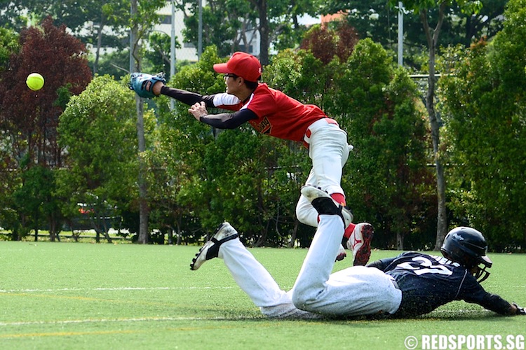 Niels (ACSI #27) dives onto first base as the ball is being overthrown. (Photo 7 © Matthew Lau/Red Sports)
