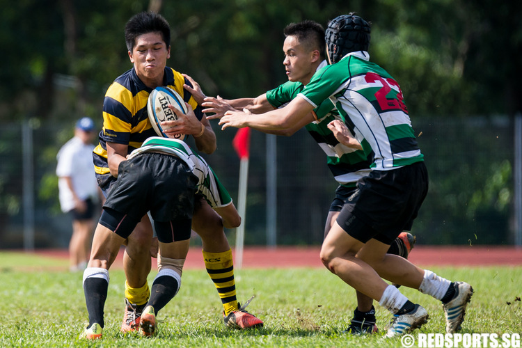 Anders Seah (#8) of Anglo-Chinese School (Independent) tries to break free from a tackle by (#10) of Raffles Institution. (Photo © Lim Yong Teck/Red Sports)