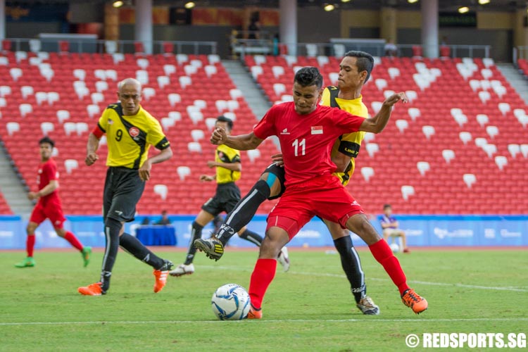 Muhammad Mubarak (#11) trying to keep possession of the ball under pressure from a Malaysian player. (Photo 5 © Jerald Ang/Red Sports)