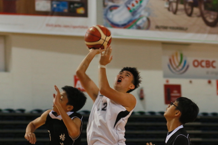 Bryan Teo (Raffles #12) attempting a field goal while closely guarded by 2 Pierce defenders.