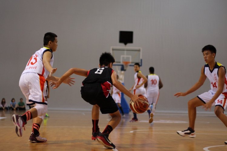 (ACSBR#6) brings the ball across the half-court line while cutting past two defenders. (Photo 1 © REDintern Adeline Lee)