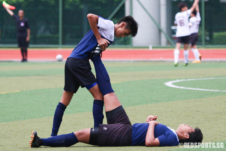 Boey Kar Wye (JJC #9) helps Muhammad Faris B Mazlan (JJC #12) who was suffering from leg cramp. (Photo © Chua Kai Yun/Red Sports)