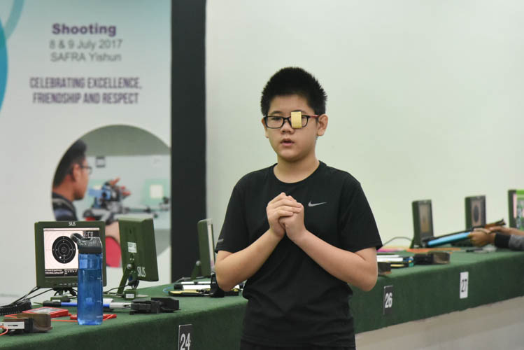 Hang Zizhou of St Hilda's Primary School reacting after a shot during the Air Pistol Men's Y13 category competition, he came in second with a score of 506. (Photo ©  Stefanus Ian/Red Sports)
