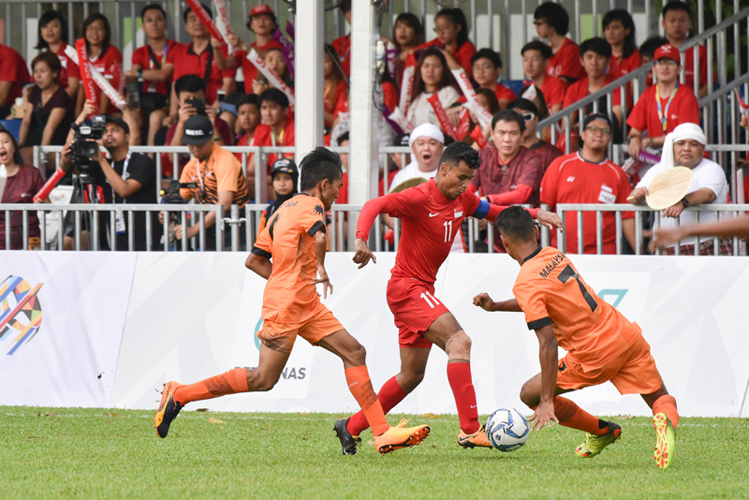 Muhammad Mubarak dribbling the ball as two Malaysian defenders close in. (Photo 1 ;copy& Stefanus Ian/Team Singapore)