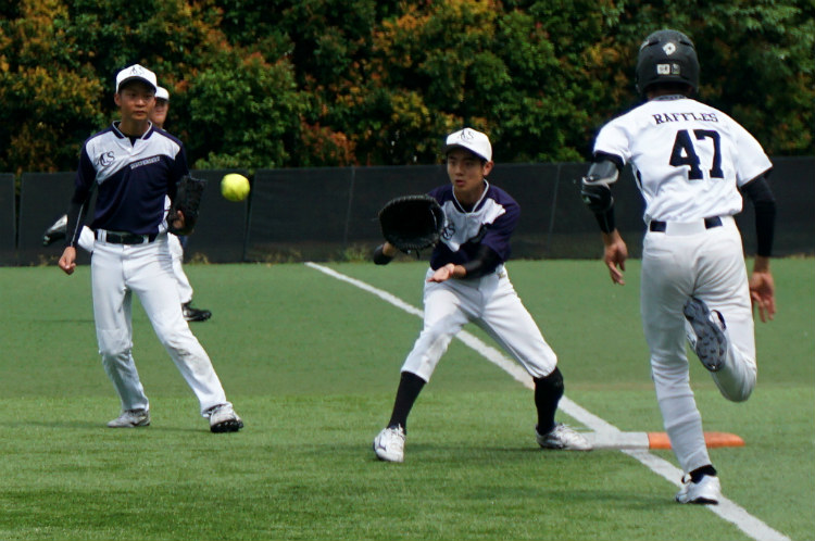 Eldon (ACSI #18) catches the ball at first base to oust Jia Ming (RI #47). (Photo 8 © REDintern Pang Chin Yee.)