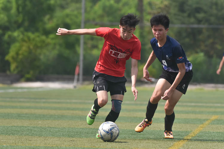 A Raffles Institution player (in red) dribbling the ball down the wings during a NYSI JC League match between Raffles Institution and River Valley High School. (Photo © Stefanus Ian/Red Sports)