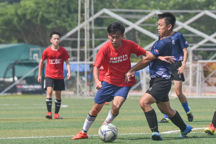 A Raffles Institution player (in red) guarding the ball inside the penalty box during a NYSI JC League match between Raffles Institution and River Valley High School. (Photo © Stefanus Ian/Red Sports)