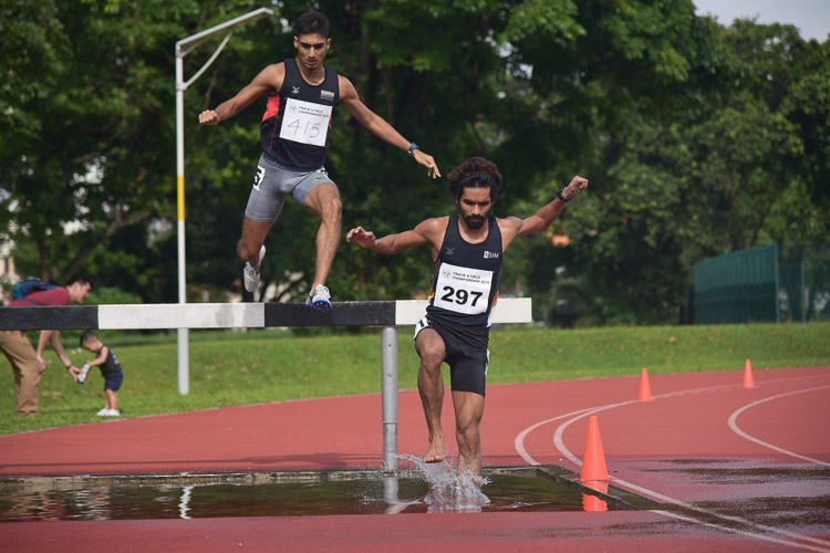 Nabin Parajuli of SIM (#297) and Karthic Harish of SUTD (#415) going through the water jump during the Men's 3000m Steeplechase race. They finished in the top two positions with a time of 9:44.04 and 10:18.99 respectively. (Photo 1 © Iman Hashim/Red Sports)