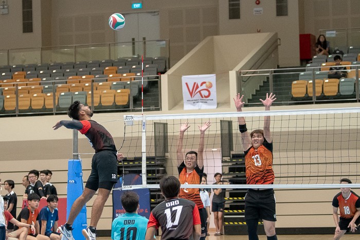 Ajay Shergill (#9) of ORD rises to meet the ball. At the net (left to right): Chaw Zhi Wei (#2) and Liew Kian Hui (#13).
