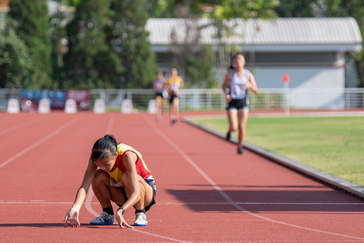 Clarice Lau Jia Yun of HCI crouches to recover after crossing the finish line of the 3000m A Division Girls' final in first place.