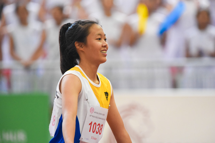 Elizabeth-Ann Tan of Nanyang Girls' High School reacts after seeing the results of the B Division girls' 100m final on the big screen, with her NYGH schoolmates cheering for her in the stands behind. (Photo 1 © Iman Hashim/Red Sports)