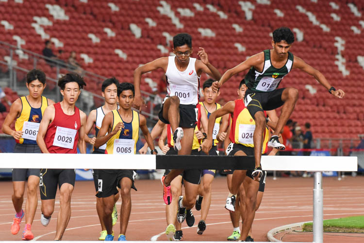 RI's Armand Mohan (in green) in a tight contest with ASRJC's Ruben Loganathan (in white) during the early stages of the A Division boys' 3000m Steeplechase final. (Photo X © Iman Hashim/Red Sports)