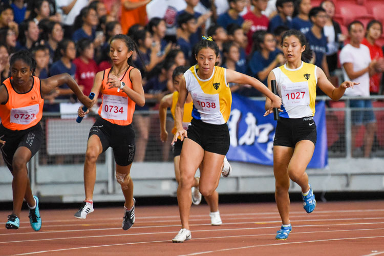 SSP's Tyeisha Khoo (#734) hands the baton over to Chandru Bhavika (#723) while NYGH's Bernice Liew (#1027) passes to Elizabeth-Ann Tan (#1038) in the B Division girls' 4x100m relay. NYGH and SSP finished in first and second respectively. (Photo 1 © Iman Hashim/Red Sports)