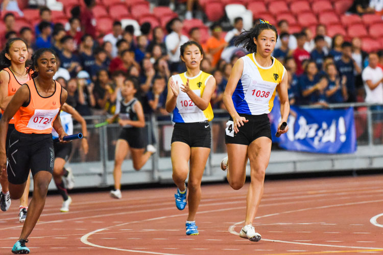 NYGH's Bernice Liew (#1027) hands over to anchor Elizabeth-Ann Tan (#1038) in the B Division girls' 4x100m relay. Their team clinched the gold in 48.30s, the second-fastest timing clocked in the history of this event. (Photo 1 © Iman Hashim/Red Sports)