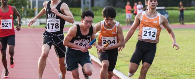 Justin Chan (#204) of NUS and Wayne Yap (#180) of NTU receive the baton almost simultaneously between the second and third legs of the Men's 4x400m Relay timed finals. NUS went on to win gold while NTU finished fifth. (Photo 1 © Iman Hashim/Red Sports)