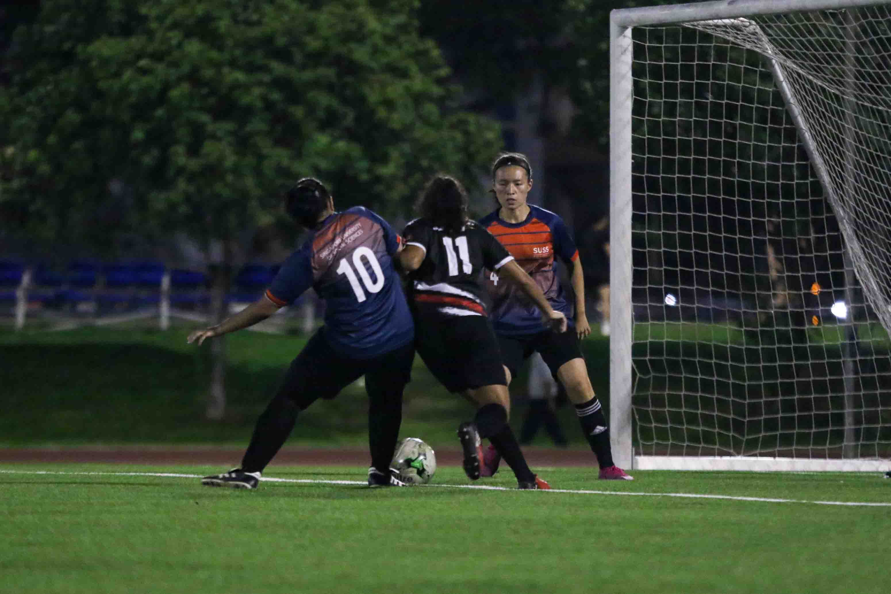 Nur Hafizah (SUSS #10) and Deanna Lim (SUSS #4) tries to prevent Vinita Sheri (SIT #11) from getting the ball in their penalty box. (Photo 6 © Clara Lau/Red Sports)