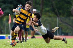 ACS(I)'s Shane O'Hehir (left) broke through the Raffles Institution's defence, as ACS(I) Sub Team 1 beat RI Sub Team 1 38-0 in the 2022 National School Games Rugby Cup semi-final match that spanned three days due to inclement weather. (Photo 3 © Bryan Foo/Red Sports)