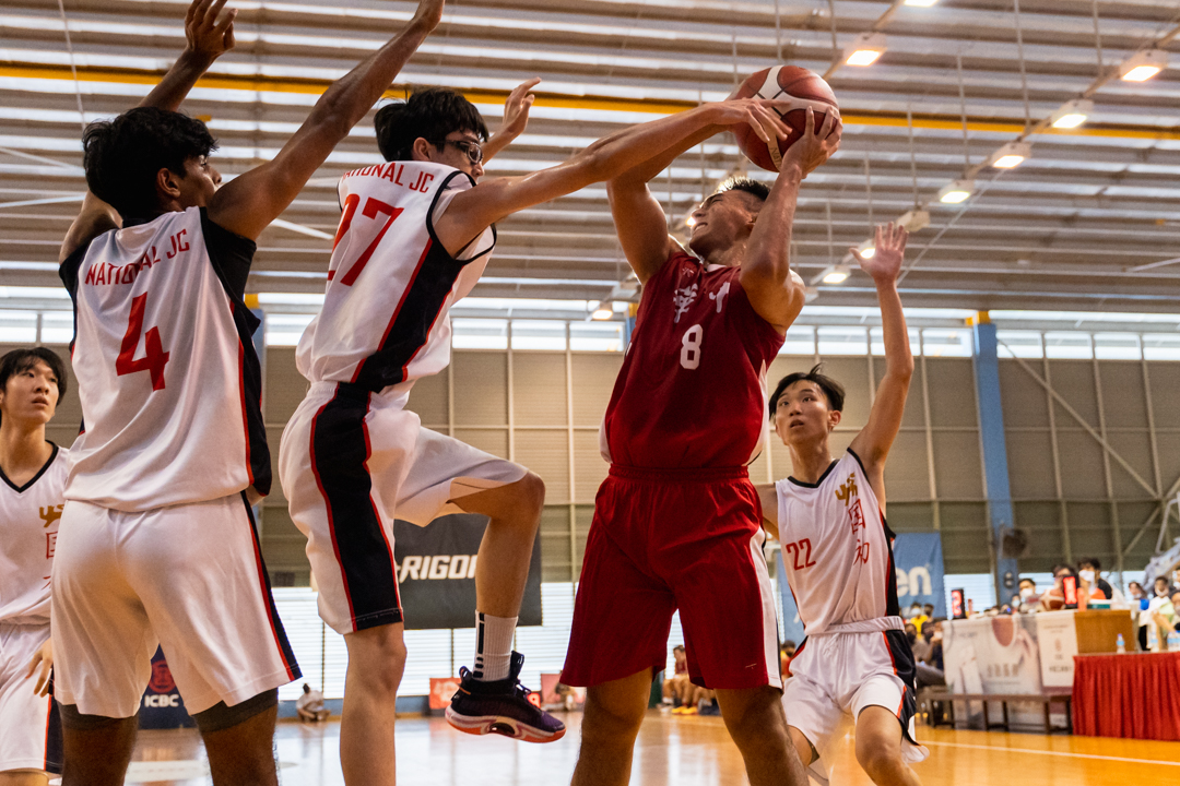 HCI's Gao Shan (centre, in red) fights off the NJC defenders for the rebound. (Photo X © Bryan Foo/Red Sports)