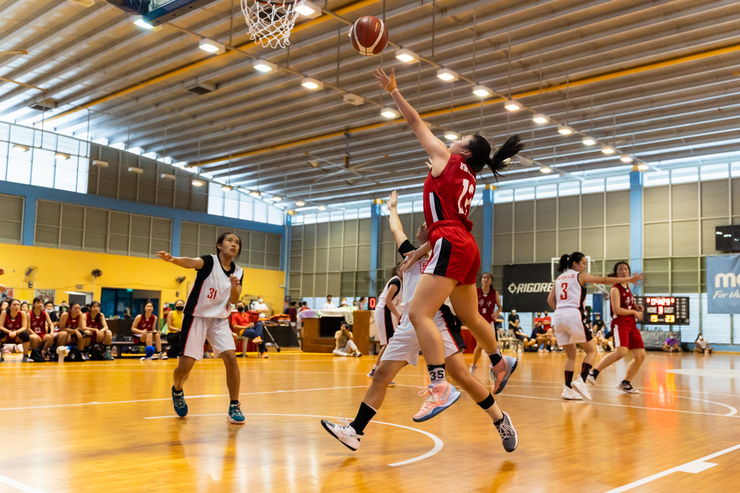 Sarah Goh (HCI #13) (right, in red) executes a layup. (Photo X © Bryan Foo/Red Sports)