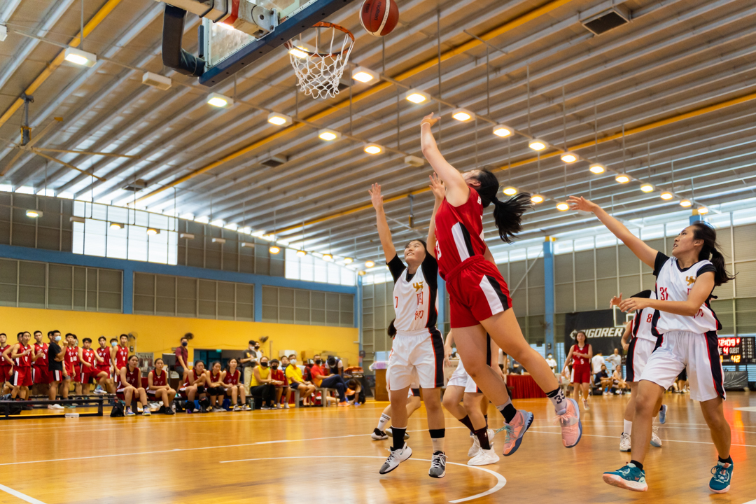 Sarah Goh (HCI #13) (right, in red) makes the layup. (Photo X © Bryan Foo/Red Sports)