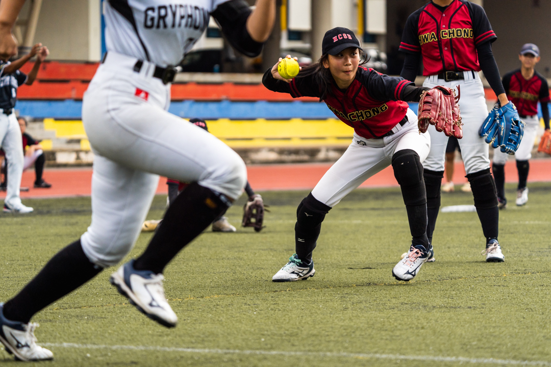 HCI player fields as she tries to get the ball to first base before the Raffles runner. (Photo X © Bryan Foo/Red Sports)