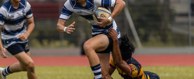 SAJC player shrugs off the tackler as he carries the ball. (Photo 3 © Bryan Foo/Red Sports)