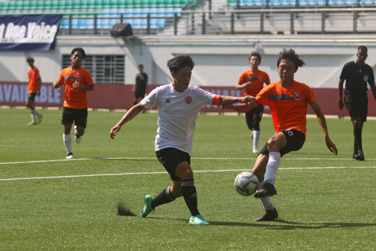 Ong E Jay (SAJC #18) clears the ball amidst oncoming pressure from VJC's captain Tan Ray Yien (#12)