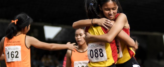 HCI's Alexia Song (#75) embraces teammate Ho Zhi Ling (#88) after the A Div girls' 4x400m relay final. (Photo 1 © Iman Hashim/Red Sports)