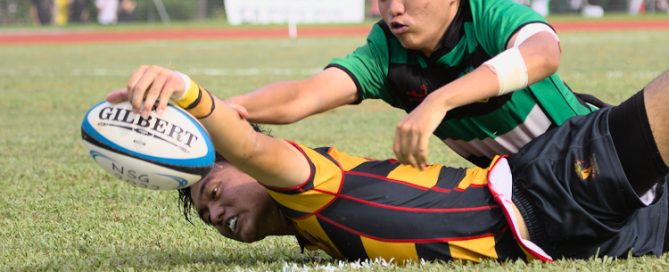 ACS(I)'s Eric Chi reaches for the try-line to score the closing try for ACS(I), after fending off the Raffles defenders. (Photo 1 © Shenn Tan/Red Sports)