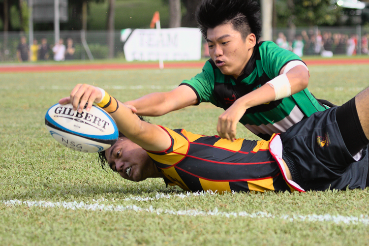 ACS(I)'s Eric Chi reaches for the try-line to score the closing try for ACS(I), after fending off the Raffles defenders. (Photo 1 © Shenn Tan/Red Sports)