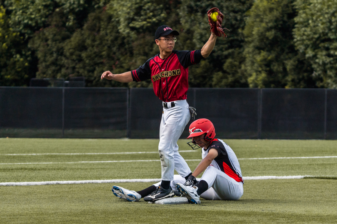 Shortstop Ze Bin (HCI #10) (left) raises his glove with the ball inside, hoping to have 'outed' the NJC runner. (Photo X © Bryan Foo/Red Sports)