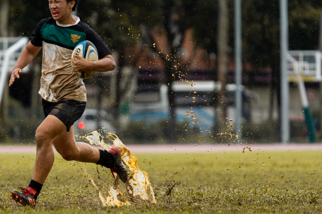 Ernest Yap (RI #6) trudges through the mud, on his way to score a try for Raffles. (Photo X © Bryan Foo/Red Sports)