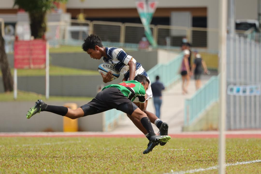 SA winger Afiq bin Muhammad (#20) is tackled into touch by opposing winger Muhammad Akif (#30).