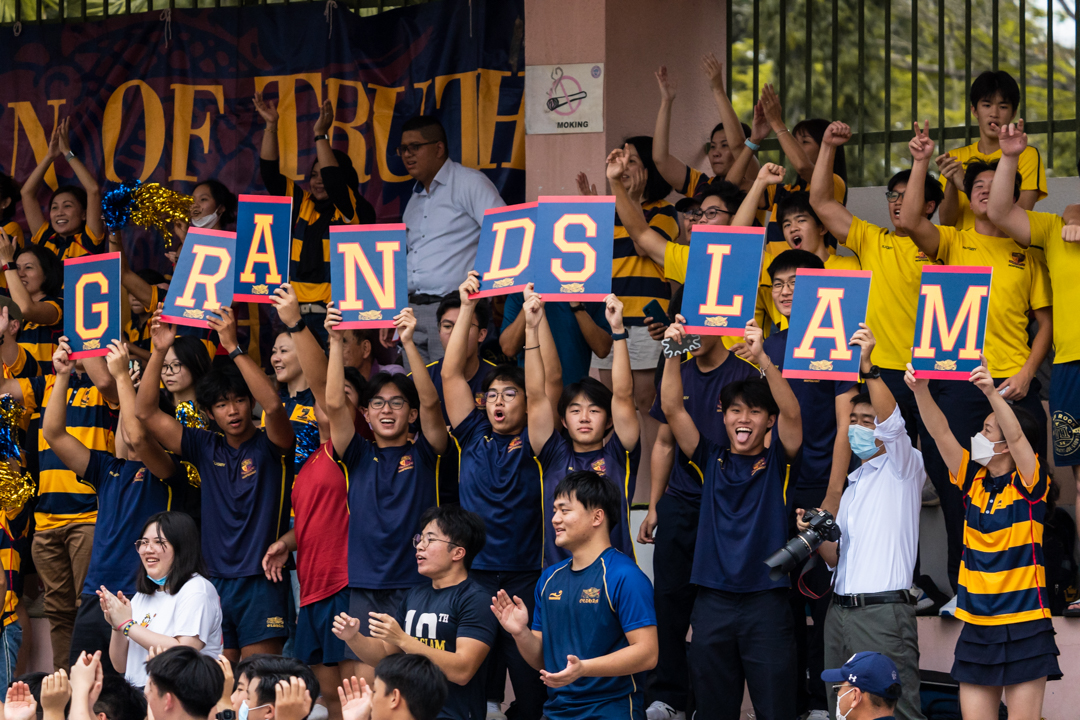 Spectating ACS(I) A Division rugby seniors raise up signs to form the word "grand slam" after the win. (Photo X © Bryan Foo/Red Sports)