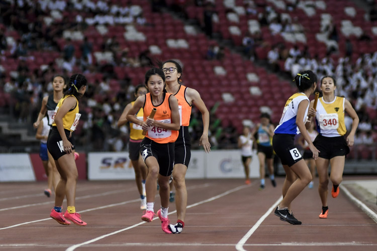 Final baton exchanges in the B Div girls' 4x400m relay final. SSP's Neo En Yu twists her ankle as she hands over the baton to anchor Victoria Chua.  SSP went on to win the gold. (Photo X © Iman Hashim/Red Sports)