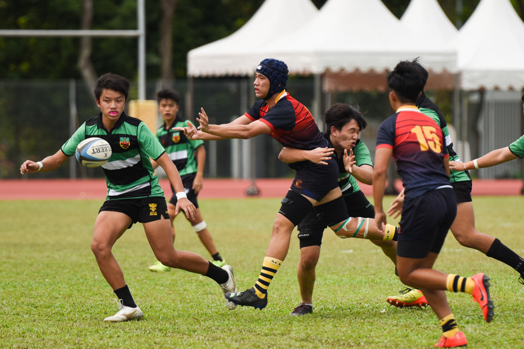 ACJC's Benjamin Yong (#6) passes the ball out as he's tackled. (Photo 21 © Jared Chow/Red Sports)