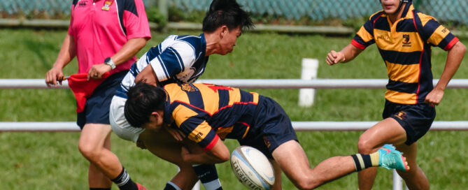 ACS(I)’s John Heng (#13) makes a textbook tackle on an SAJC player as he spills the ball. (Photo 3 © Jared Chow/Red Sports)
